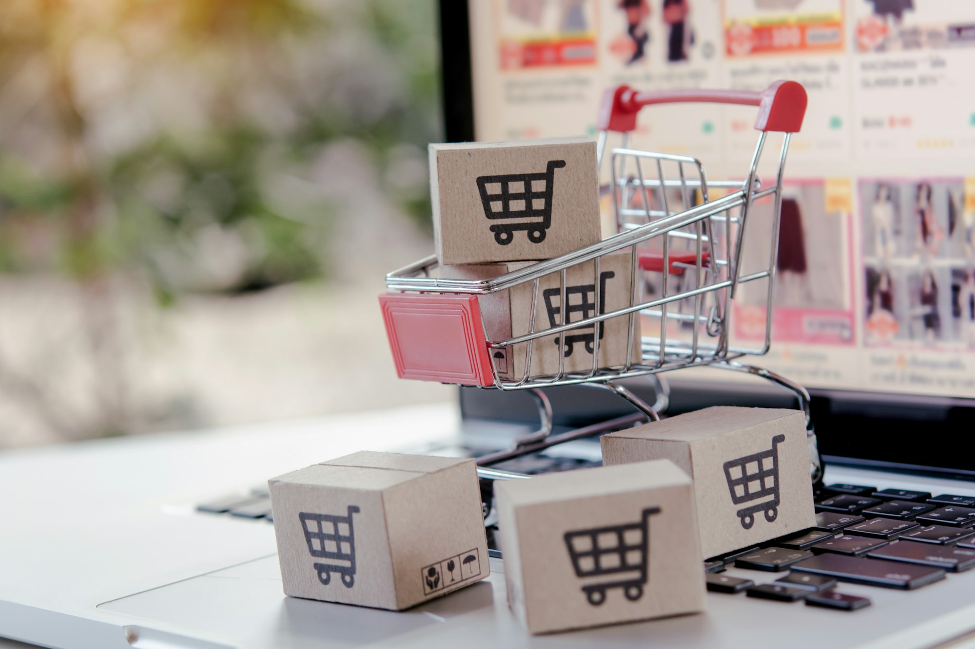 cardboard box with a shopping cart logo in a trolley on laptop keyboard